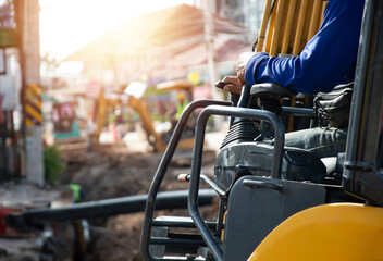 The excavator driver is controlling the operation of the vehicle.
