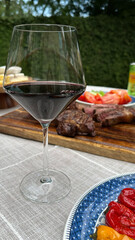 Elegant glass of red wine outdoors with juicy steak and fresh vegetables - concept of fine dining, bbq restaurants, catering services