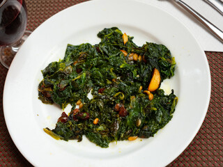 There is portion of dietary side dish on plate - Catalan spinach. Dish is steamed, with addition of...