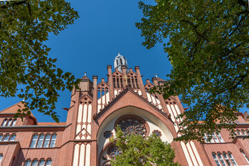 Church exterior, facade with tower. Neo-Gothic facade of a red brick church with a large rose...