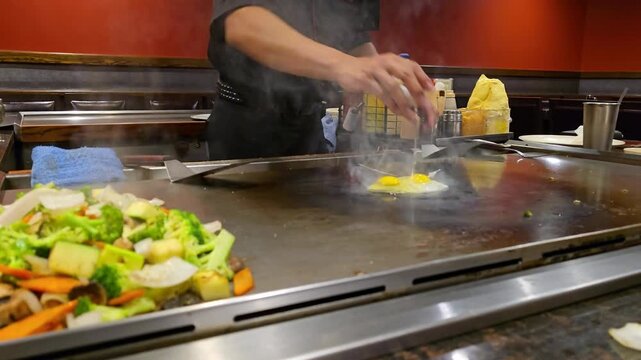 Hibachi chef cooking eggs for a delicious meal with kitchen restaurant background