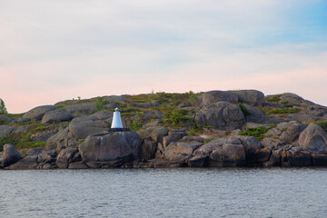 Marine channel marker on coastal rocks, indicating the edge of the channel. Coastal navigation aid in Baltic sea, highlighting safety, marine guidance, and rocky shoreline