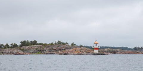 Marine channel marker on coastal rocks, indicating the edge of the channel. Coastal navigation aid in Baltic sea, highlighting safety, marine guidance, and rocky shoreline