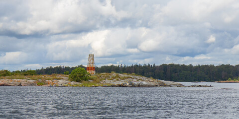 Marine marker made of stacked stones on the shore. Coastal navigation aid in Baltic sea, marking channel edges, blending natural materials with maritime safety in rocky environment
