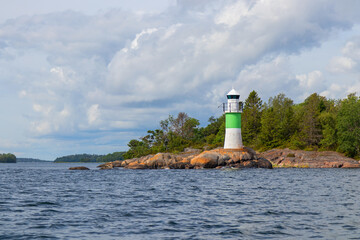 Marine channel marker on coastal rocks with green top, indicating the edge of the channel. Coastal navigation aid in Baltic sea, highlighting safety, marine guidance, and rocky shoreline