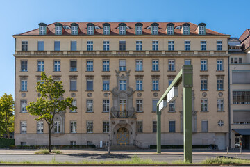 Symmetrical front of a large old Berlin building with a richly decorated entrance gate. Green...