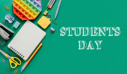 Colorful stationery and supplies arranged on green background for Students Day celebration