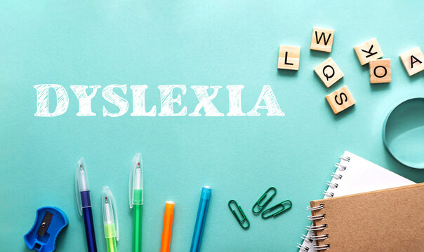 Colorful stationery items arranged around the word dyslexia on a turquoise background for educational purposes