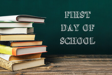 Stacked books on wooden table with chalkboard background and text about school beginnings