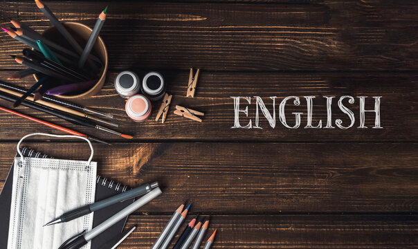 Art supplies arranged on wooden table with colorful pencils, paint, and English text for creative projects
