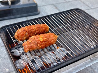 Grilling delicious meat rolls on a portable barbecue for a summer cookout feast