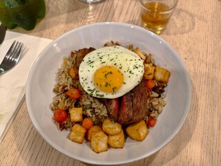 Delicious steak and egg rice bowl with fried potatoes and cherry tomatoes meal