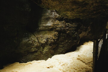 Fast mountain river flowing through narrow rocky gorge with foamy rapids, view from tourist path with safety fence.