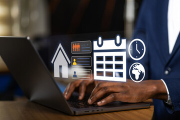 African business professional using a laptop with a holographic display to plan a corporate event calendar and coordinate with international remote team.