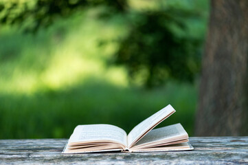 Open book on rustic wooden table outdoors