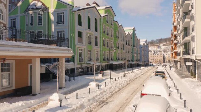 Beautiful city street with modern buildings on a winter day. Man cleaning snow with a snow thrower after snowfall. Winter in Kyiv.