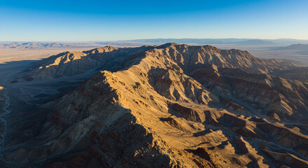 Aerial view of a vast desert landscape with rugged mountains under a clear blue sky at daytime view