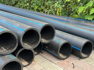 Stack of high-density polyethylene pipes. Wide black plastic pipes at a construction site in the...