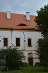 The facade of a charming old building with a red tile roof, white chimneys, and a distinctive, eye-like eyebrow dormer window
