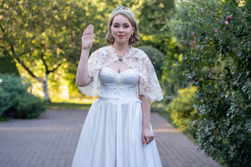 Elegant bride in a white lace wedding dress raises her hand in a graceful, almost regal gesture....