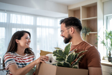 Happy couple unpacking belongings in new home after moving in