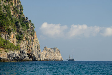 Sailing ship near rocky cliffs and blue sea