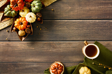 Autumn fall flat lay composition with cup of tea, pumpkins, decorative candles on wooden table....