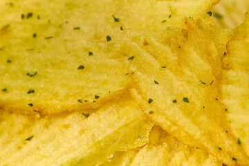 Crunchy potato chips stacked neatly with a golden hue and flecks of seasoning visible in close-up detail