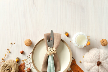 Rustic autumn table setting with plush pumpkin, candle, nuts, twine, and leaf ornament. Cozy flat...
