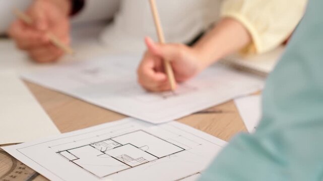 Architect and safety engineer discussion about building blueprint displaying on laptop on table with architectural document and wooden block scatter around at modern office. Closeup. Delineation.