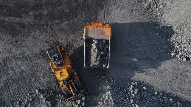 Aerial view Heavy industrial excavator loader of gold ore to dump truck, mining industry open pit mine.