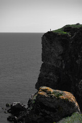 Lone Human Stands at the Edge of a Towering Cliff Overlooking a Vast Sea