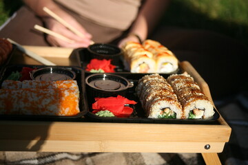 The girl eats sushi outdoors and relaxes.