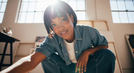 Young black female artist smiling in her sunlit studio. Low angle portrait of a creative African American woman in her workshop.