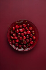cherries in a red bowl on red background