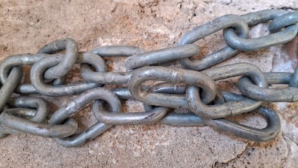 Close-up of a Heavy Duty Metal Chain Resting on a Rough Concrete Surface