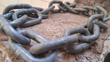 Close-up of a metal chain coiled on a rough, textured surface
