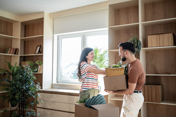Happy couple arranging plants in new home after moving in