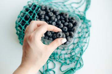 Hand picking fresh blueberries with eco-friendly bag