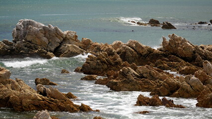 Scenic rocky coastline in Cape Town South Africa with sharp stone formations and ocean waves...