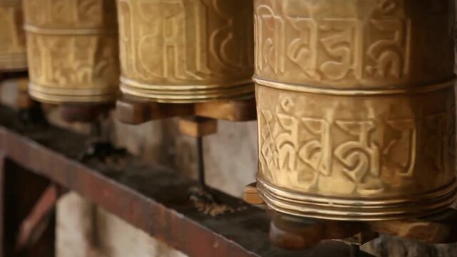 Close up of golden prayer wheels with engravings at a buddhist monastery