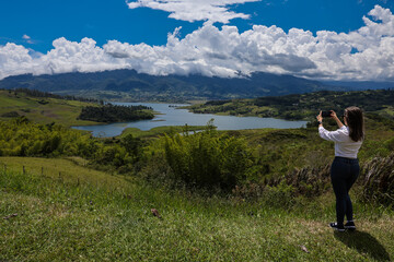 Female tourist taking pictures at the biggest artificial lake in Colombia called Calima Lake located on the mountains of Darien at the region of Valle del Cauca