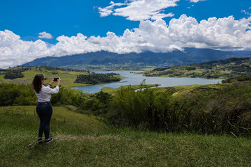 Female tourist taking pictures at the biggest artificial lake in Colombia called Calima Lake located on the mountains of Darien at the region of Valle del Cauca