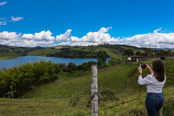 Female tourist taking pictures at the biggest artificial lake in Colombia called Calima Lake located on the mountains of Darien at the region of Valle del Cauca