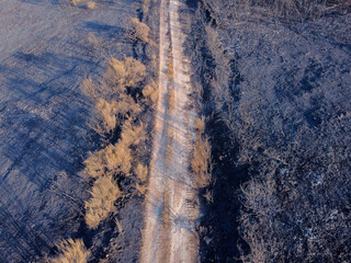 A Dirt Road Through a Burnt Landscape from Above. Concept The lonely path through destruction.