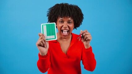 Joyful young woman exuberantly showcasing her new driving license while holding car keys, embodying excitement and pride in her achievement, ready to embark on new adventures on the road ahead