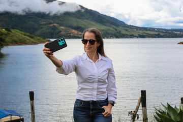 Female tourist taking pictures at the biggest artificial lake in Colombia called Calima Lake located on the mountains of Darien at the region of Valle del Cauca