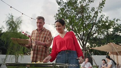 Family all together camp in garden, Old couple cooking BBQ, having a meal. Senior use outdoor camping activity, relax with nature and spend time with young generation cross generation gap. Divergence.