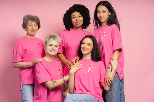 Interracial group of smiling women wearing pink ribbons supporting breast cancer awareness