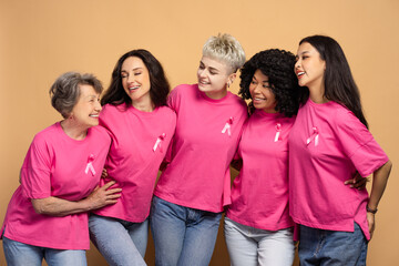 Diverse group of women embracing wearing pink t shirts with ribbons for breast cancer awareness